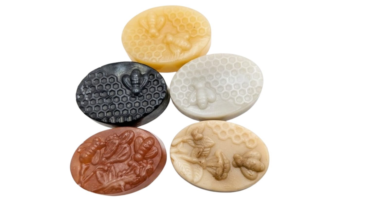 Five unwrapped Gul Beauty Soap bars — ubtan, charcoal, rice, coffee and whitening — each pressed with a honeycomb and bee pattern